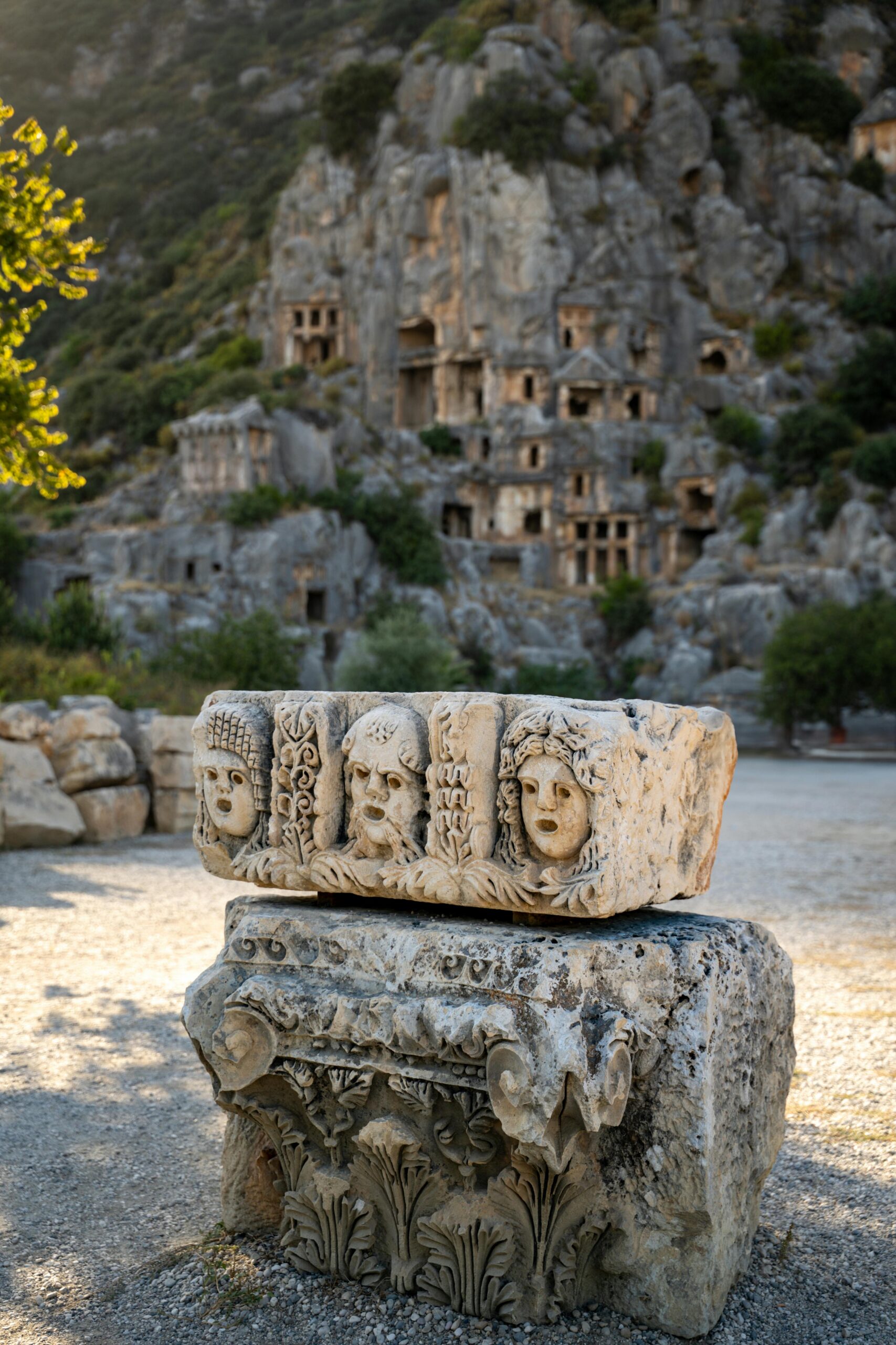 Historic rock tombs and carved stone in Myra, Turkey, against a rocky landscape.