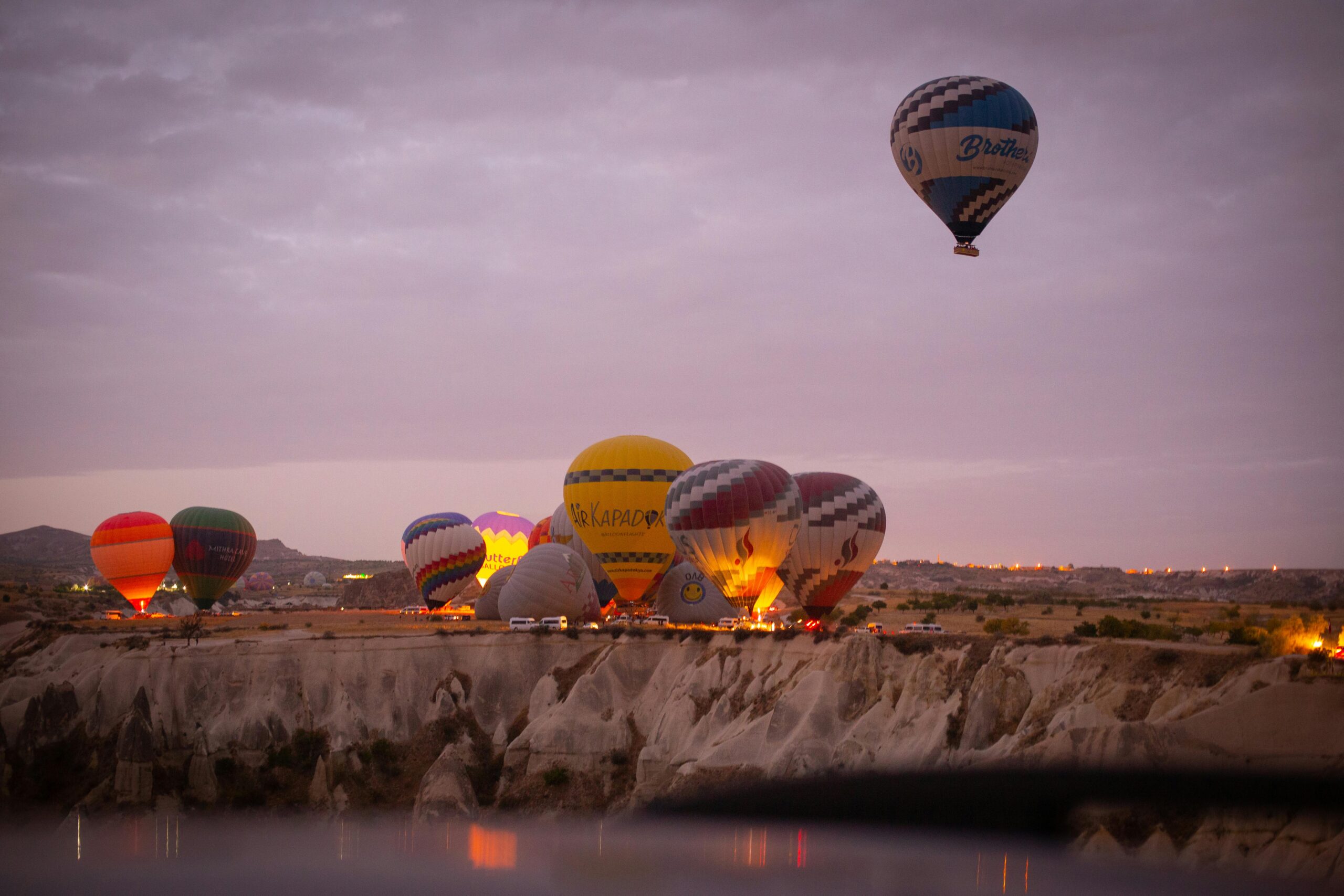 Colorful hot air balloons soar over Cappadocia, Turkey at sunrise, creating a stunning aerial view.